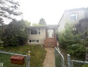 Stucco exterior residence featuring a covered entry, wooden stairs, and a concrete walkway - 9640 74 Avenue, Edmonton, AB 