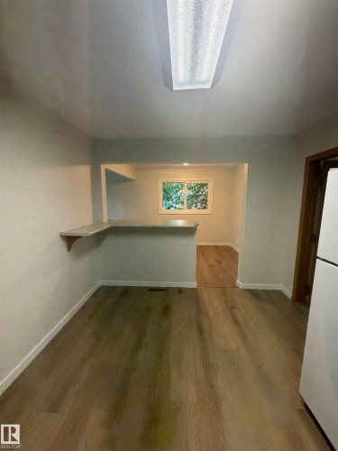 Open-concept living area featuring wood-finish flooring, a breakfast bar, and a window providing natural light - 9640 74 Avenue, Edmonton, AB 