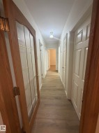 Hallway featuring wood-finish flooring, white paneled doors, and a decorative flush-mount ceiling light - 