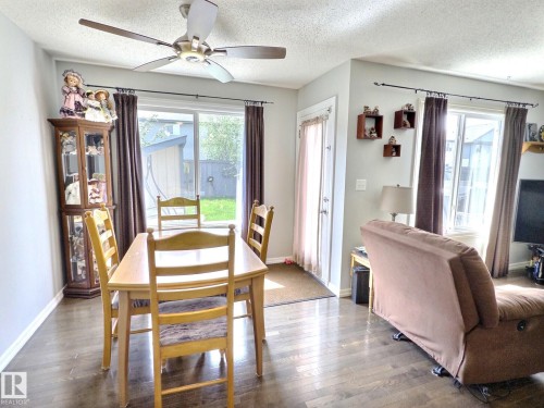 Open-concept living area featuring wood-finish flooring, a ceiling fan, and large windows providing ample natural light - 126 Calvert Wynd, Fort Saskatchewan, AB 