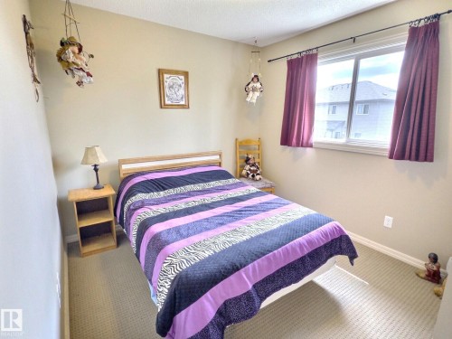 Neutral-toned room featuring a large window with burgundy drapes, light-colored walls, and carpet flooring - 126 Calvert Wynd, Fort Saskatchewan, AB 