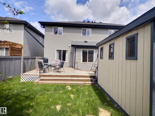 Expansive backyard featuring a manicured lawn, a multi-level wood deck, and a detached shed with multiple windows - 126 Calvert Wynd, Fort Saskatchewan, AB 