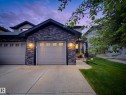 Contemporary exterior featuring stacked stone accents, two paneled garage doors with upper window inserts, and a concrete driveway - 126 Calvert Wynd, Fort Saskatchewan, AB 