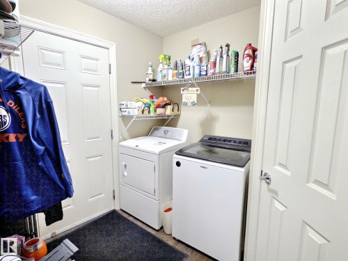 Dedicated laundry area featuring wire shelving, wood-finish flooring, and two paneled doors - 126 Calvert Wynd, Fort Saskatchewan, AB 