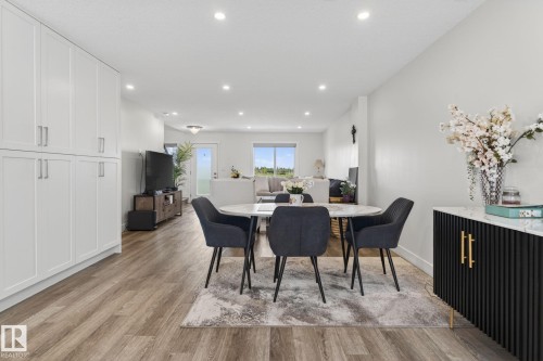 Open-concept living space featuring wood-finish flooring, recessed lighting, white walls, and a built-in storage cabinet system - 16 9250 156 Avenue, Edmonton, AB 