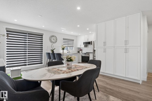 Open-concept kitchen and dining area featuring a white subway tile backsplash, stainless steel appliances, and extensive white cabinetry - 16 9250 156 Avenue, Edmonton, AB 