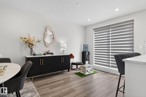 Open-concept living area featuring wood-finish flooring, recessed lighting, and a large window with horizontal blinds - 16 9250 156 Avenue, Edmonton, AB 