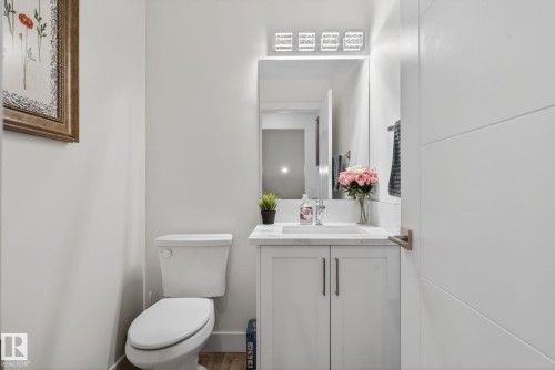 Bathroom featuring a vanity with a white countertop and base cabinetry, a wall-mounted mirror, and a contemporary light fixture - 16 9250 156 Avenue, Edmonton, AB 