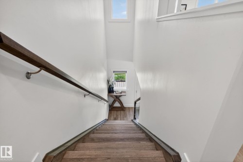 Staircase featuring wood-finish treads, a dark wood handrail with brushed nickel mounts, and white painted walls - 16 9250 156 Avenue, Edmonton, AB 