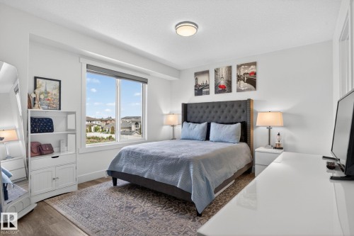 Bedroom featuring a large window, wood-finish flooring, and a flush-mount ceiling light fixture - 16 9250 156 Avenue, Edmonton, AB 
