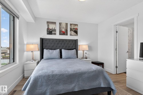 Bright interior featuring wood-finish flooring, a contemporary window with roller shade, and a white interior door - 16 9250 156 Avenue, Edmonton, AB 