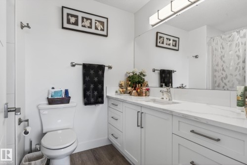 Bathroom featuring a white vanity with slab drawers and shaker-style doors, integrated sink, and a large mirror - 16 9250 156 Avenue, Edmonton, AB 