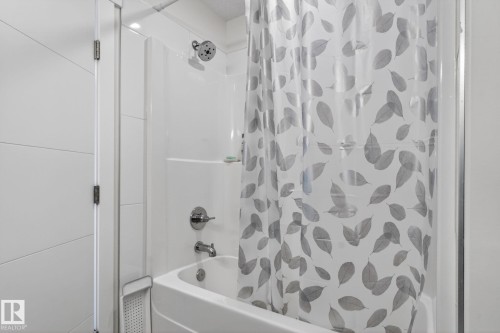 Tub and shower combination featuring a white surround, chrome fixtures, and a glass partition - 16 9250 156 Avenue, Edmonton, AB 