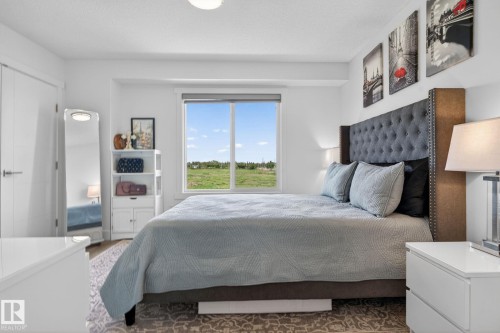 Bright bedroom featuring a large window, plush tufted headboard, and recessed ceiling lighting - 16 9250 156 Avenue, Edmonton, AB 