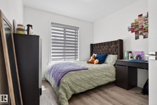 Room featuring wood-finish flooring, a window with horizontal blinds, and a built-in dark wood desk - 16 9250 156 Avenue, Edmonton, AB 