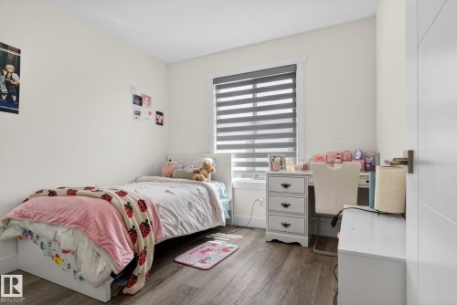 Bedroom featuring wood-finish flooring, a window with horizontal blinds, and a white interior door with contemporary hardware - 16 9250 156 Avenue, Edmonton, AB 