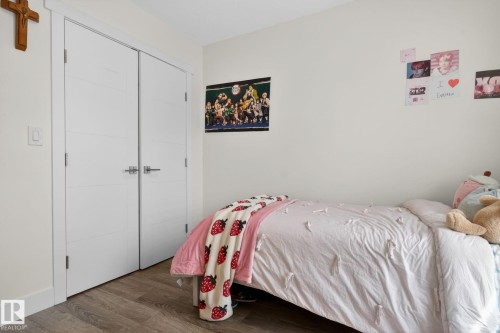 Interior room featuring wood-finish flooring, white walls, and a pair of modern closet doors with horizontal detailing and brushed nickel hardware - 16 9250 156 Avenue, Edmonton, AB 