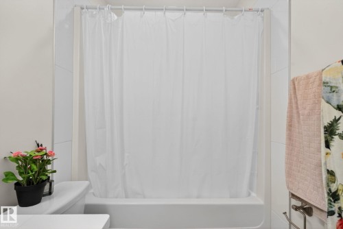 White porcelain bathtub with integrated shower, surrounded by white subway tile walls - 16 9250 156 Avenue, Edmonton, AB 