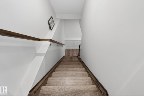 Staircase with wood-finish treads and risers, complemented by a dark wood-finish handrail - 16 9250 156 Avenue, Edmonton, AB 