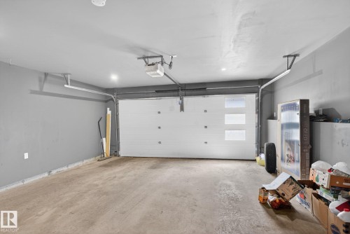 Spacious garage featuring a concrete floor, painted walls, overhead lighting, and an automatic garage door opener - 16 9250 156 Avenue, Edmonton, AB 
