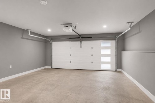 Garage with a modern white sectional door featuring four frosted horizontal window panels - 16 9250 156 Avenue, Edmonton, AB 