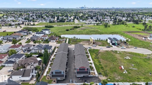 Aerial perspective showcasing new construction townhomes with dark shingle roofs and mixed material exteriors - 16 9250 156 Avenue, Edmonton, AB 