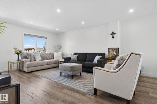 Spacious living area featuring wood-finish flooring, recessed lighting, and ample natural light from a large window - 16 9250 156 Avenue, Edmonton, AB 