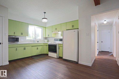 Kitchen featuring abundant cabinetry, dual-basin stainless steel sink, tile backsplash, and wood-finish flooring - 10 Murray Crescent, St. Albert, AB 