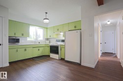 Kitchen featuring abundant cabinetry, dual-basin stainless steel sink, tile backsplash, and wood-finish flooring - 