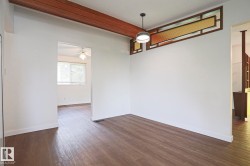 Open interior space featuring wood-finish flooring, white baseboards, and a modern ceiling fixture - 
