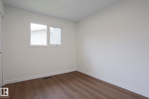 Bright room with wood-finish flooring, white walls, and a large window - 10 Murray Crescent, St. Albert, AB 