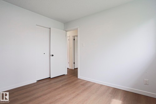 Neutral white walls with matching baseboards, wood-finish flooring, and a large bi-fold closet - 10 Murray Crescent, St. Albert, AB 