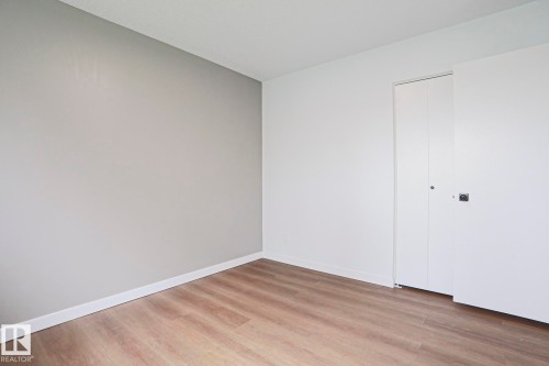 Room featuring wood-finish flooring, white baseboards, and a light gray accent wall - 10 Murray Crescent, St. Albert, AB 