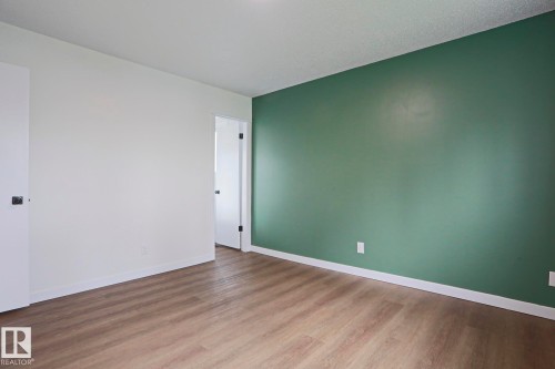 Room with wood-finish flooring, a feature wall in a muted green hue, and white baseboards - 10 Murray Crescent, St. Albert, AB 