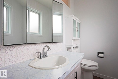 Bathroom featuring a vanity with an integrated sink, a chrome faucet, and a patterned backsplash - 10 Murray Crescent, St. Albert, AB 