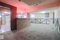 Finished basement space featuring a brick-clad bar, textured wall paneling, and wall-to-wall carpeting - 