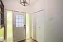 Entryway featuring a white paneled door with grid-patterned glass, flanked by two textured glass sidelights, wood-finish flooring, and a contemporary ceiling light fixture - 10 Murray Crescent, St. Albert, AB 