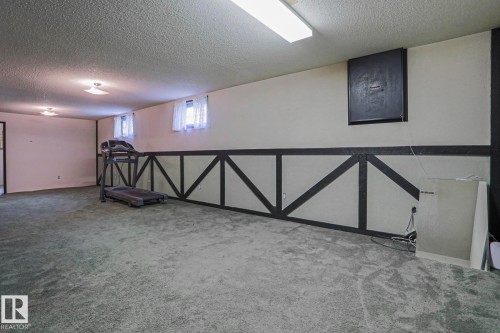 Spacious carpeted room featuring a drop ceiling with recessed lighting and a fluorescent light fixture - 10 Murray Crescent, St. Albert, AB 