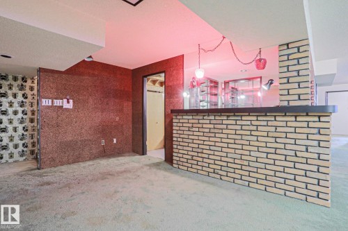 Brick-faced bar with a dark countertop, glass shelving, and a built-in sink - 10 Murray Crescent, St. Albert, AB 