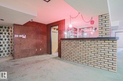 Brick-faced bar with a dark countertop, glass shelving, and a built-in sink - 
