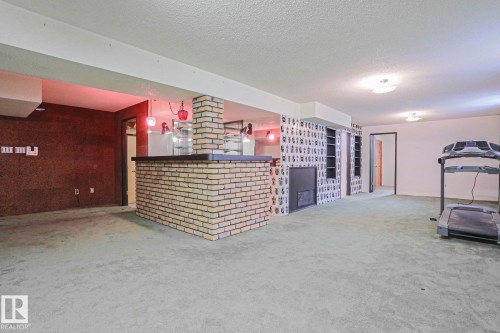 Spacious lower level featuring a brick-faced bar, integrated shelving, and a built-in fireplace - 10 Murray Crescent, St. Albert, AB 