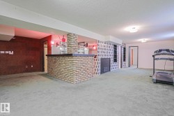 Spacious lower level featuring a brick-faced bar, integrated shelving, and a built-in fireplace - 