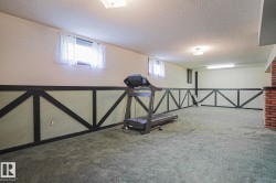 Spacious finished basement featuring patterned wall paneling, recessed lighting, and a brick-finish accent wall - 