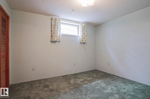 Room featuring textured ceiling, light-toned walls, and a window with patterned curtains - 10 Murray Crescent, St. Albert, AB 
