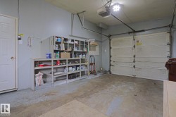 Spacious garage with an overhead door, concrete flooring, built-in shelving, and direct interior access - 