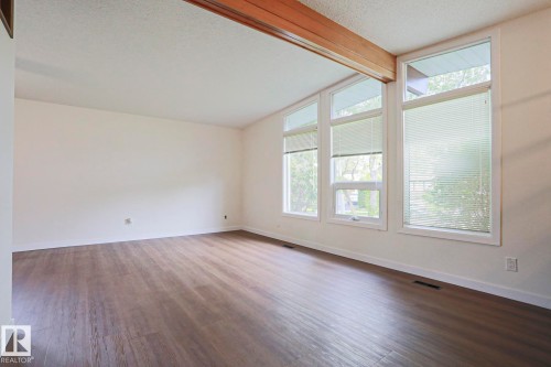 Room featuring wood-finish flooring, white walls, and a wood beam accent - 10 Murray Crescent, St. Albert, AB 