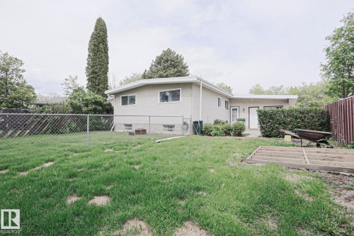 Expansive backyard featuring a partial chain-link fence, a mature tree line, and a partially constructed wood deck frame - 10 Murray Crescent, St. Albert, AB 