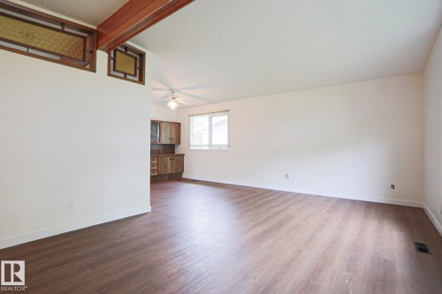 Spacious room featuring wood-finish flooring, white walls, and a recessed window - 10 Murray Crescent, St. Albert, AB 