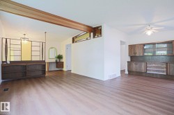 Spacious interior with wood-finish flooring, exposed ceiling beam, and a decorative room divider - 