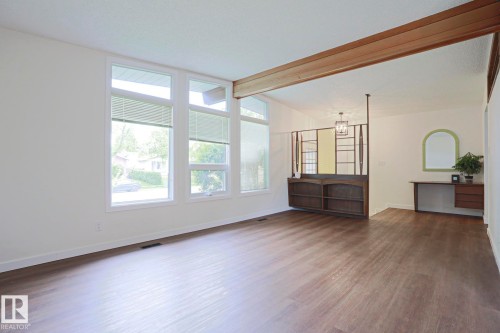 Spacious interior featuring wood-finish flooring, a prominent exposed beam, and multiple large windows - 10 Murray Crescent, St. Albert, AB 